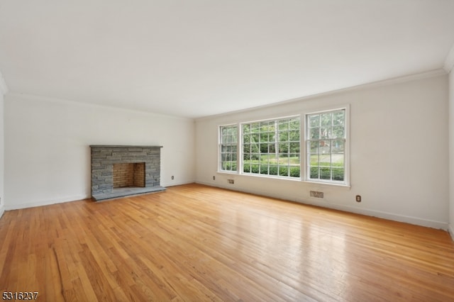 unfurnished living room featuring ornamental molding, light hardwood / wood-style floors, and a stone fireplace