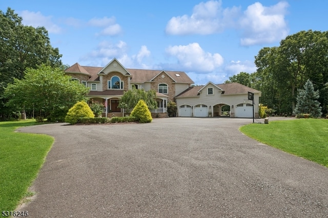 view of front of home with covered porch, a garage, and a front lawn