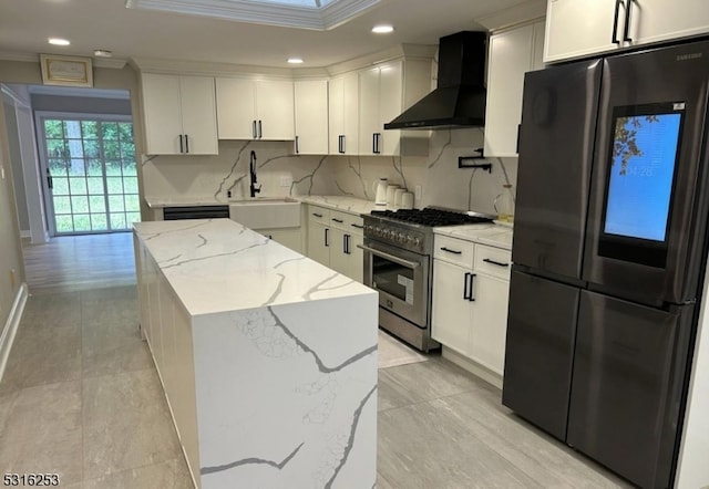 kitchen with a kitchen island, light stone countertops, fridge, high end range, and wall chimney range hood