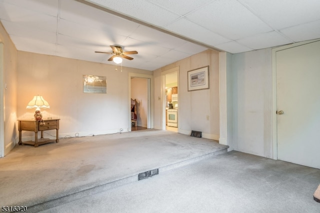 carpeted spare room with a drop ceiling and ceiling fan