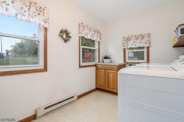 clothes washing area featuring cabinets, a baseboard radiator, washer and clothes dryer, and a wealth of natural light