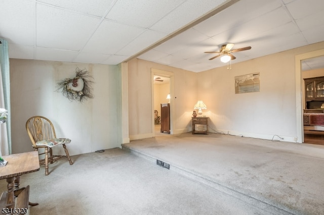 carpeted empty room featuring ceiling fan and a paneled ceiling