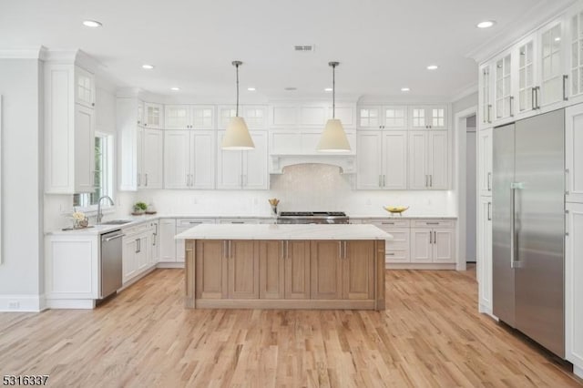 kitchen with pendant lighting, stainless steel appliances, a center island, and white cabinets