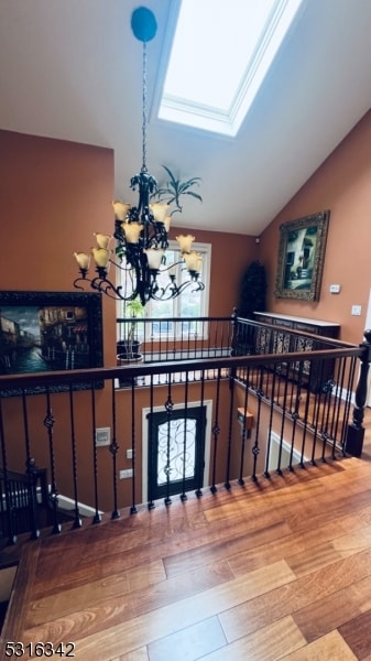 stairs featuring an inviting chandelier, hardwood / wood-style flooring, and vaulted ceiling with skylight