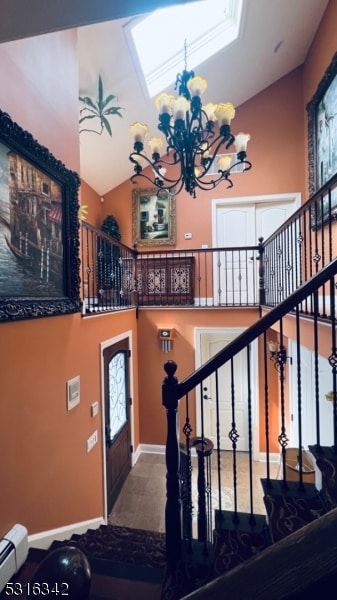 entryway with a notable chandelier, baseboard heating, and lofted ceiling with skylight