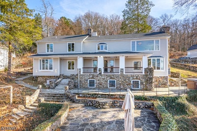 back of property with a chimney, a patio area, stairway, and fence