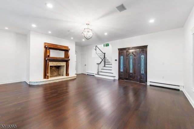 unfurnished living room with wood finished floors, a notable chandelier, baseboard heating, a fireplace with raised hearth, and a baseboard radiator