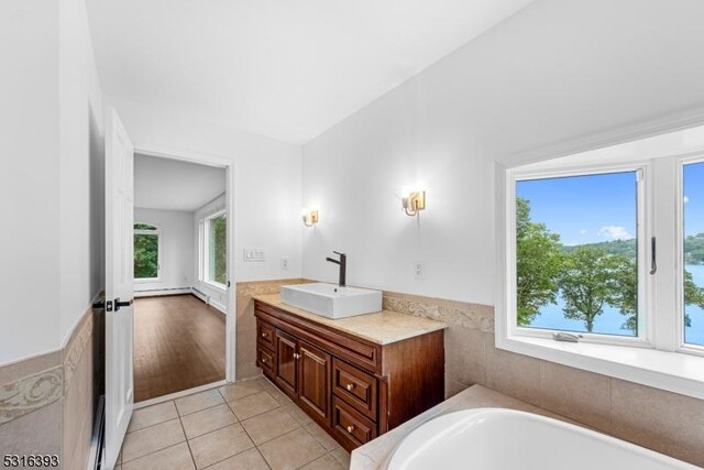 full bathroom with tile patterned flooring, a baseboard radiator, vanity, and a washtub