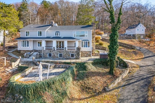 rear view of property with stairway, stone siding, fence, and a chimney