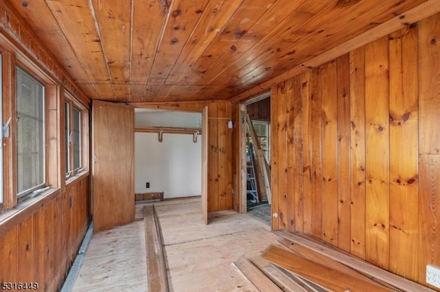 empty room featuring wood ceiling and wooden walls
