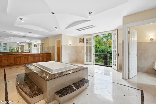 bathroom featuring french doors, tile walls, a bath, and tile patterned floors