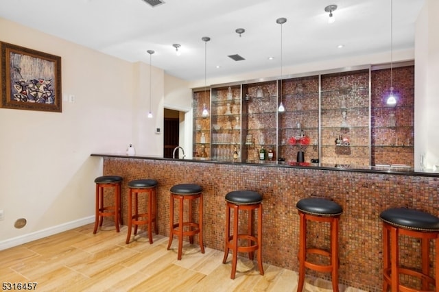 bar featuring wood-type flooring, hanging light fixtures, and sink