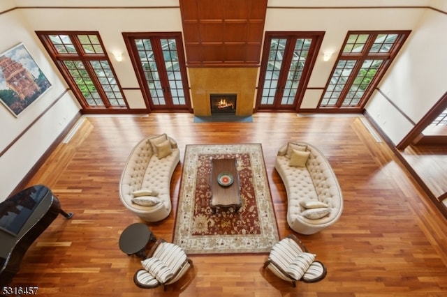 living room featuring wood-type flooring, a towering ceiling, and a wealth of natural light