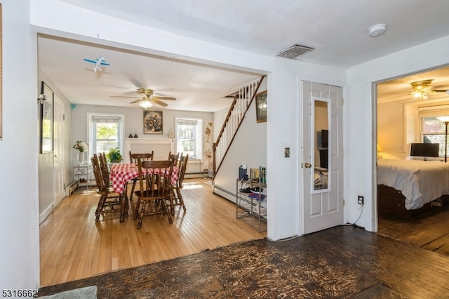 dining room with wood-type flooring, ceiling fan, and a baseboard radiator