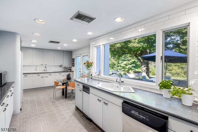 kitchen featuring stainless steel dishwasher, white cabinetry, and a wealth of natural light