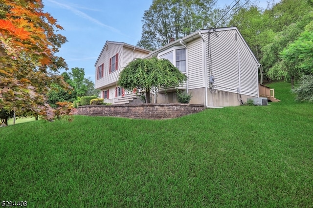 view of side of property featuring central AC unit and a lawn