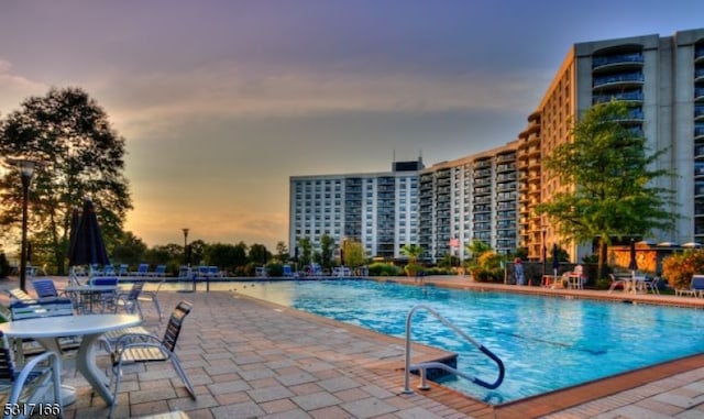 pool at dusk with a patio area