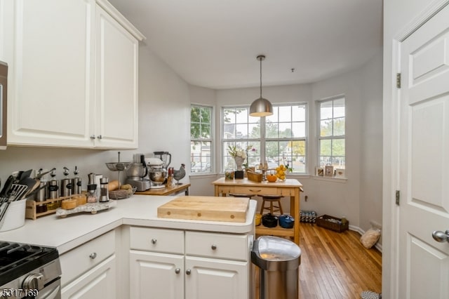 kitchen featuring wood-type flooring, white cabinetry, and hanging light fixtures