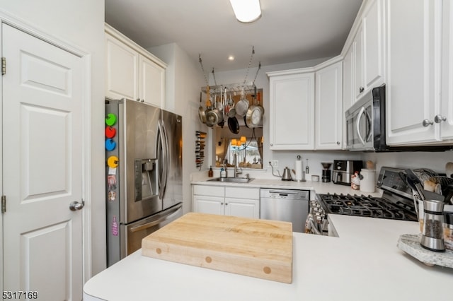 kitchen with white cabinets, kitchen peninsula, appliances with stainless steel finishes, and sink