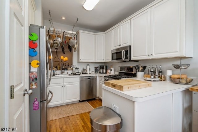 kitchen featuring appliances with stainless steel finishes, light wood-type flooring, and white cabinetry