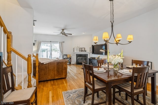 dining room featuring ceiling fan with notable chandelier and light hardwood / wood-style floors