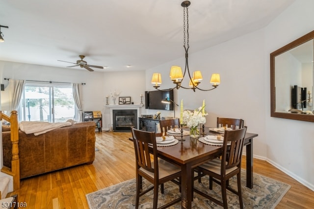 dining space featuring ceiling fan with notable chandelier and hardwood / wood-style flooring