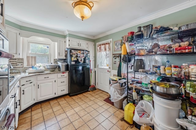 kitchen featuring white cabinets, decorative backsplash, light tile patterned floors, crown molding, and black refrigerator