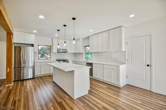 kitchen featuring white cabinets, hanging light fixtures, a kitchen island, light hardwood / wood-style flooring, and stainless steel appliances