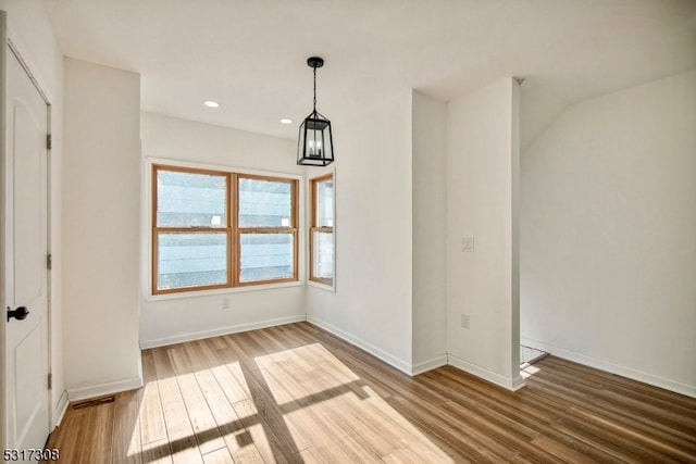 unfurnished dining area featuring a chandelier and hardwood / wood-style flooring