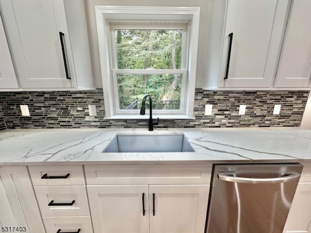 kitchen with sink, white cabinetry, light stone counters, and stainless steel dishwasher