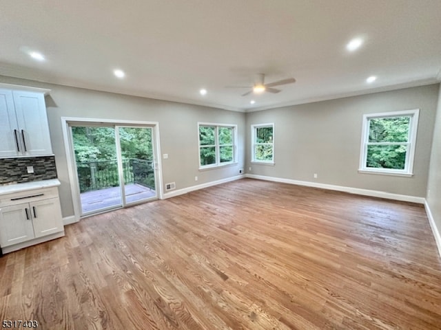 unfurnished living room featuring a healthy amount of sunlight, ceiling fan, and light hardwood / wood-style flooring