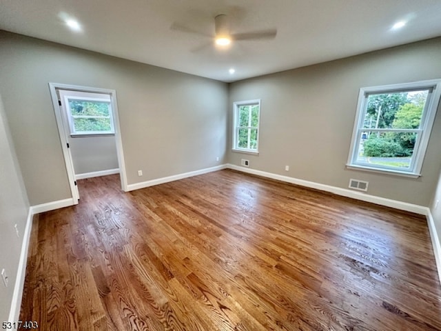 spare room featuring ceiling fan, hardwood / wood-style flooring, and a healthy amount of sunlight