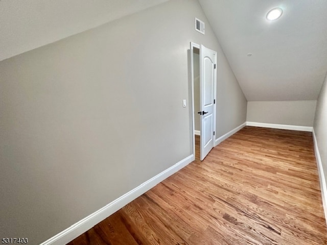 additional living space with light hardwood / wood-style flooring and vaulted ceiling