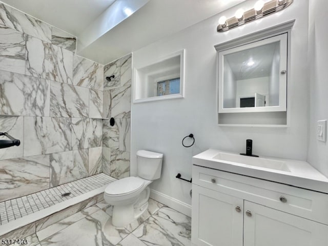 bathroom featuring a tile shower, vanity, and toilet