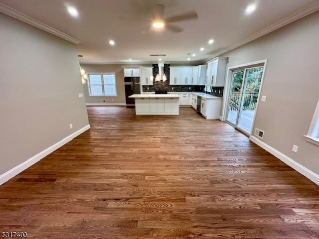 kitchen with white cabinets, crown molding, dark wood-type flooring, and wall chimney range hood