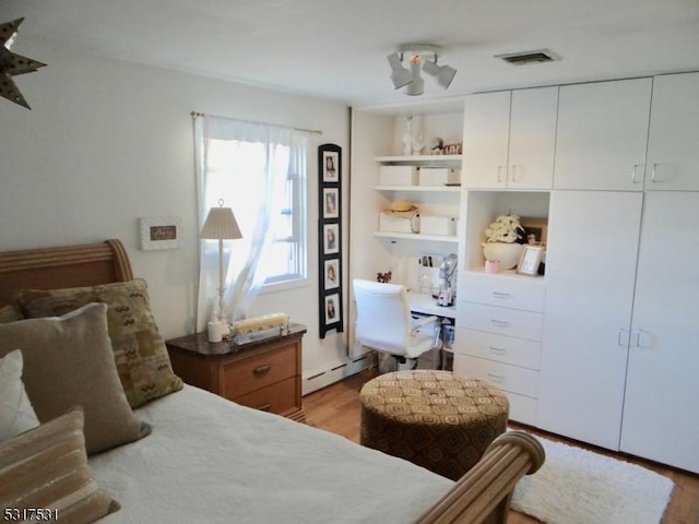 bedroom with light wood-style floors, visible vents, and a baseboard radiator