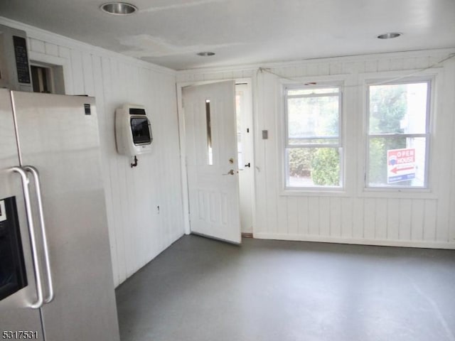 interior space with heating unit, stainless steel fridge, and concrete flooring