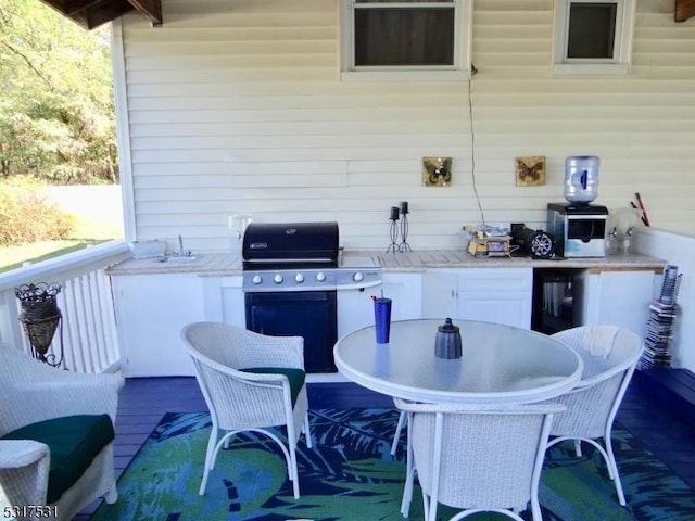 view of patio with grilling area, beverage cooler, outdoor dining area, a deck, and a sink