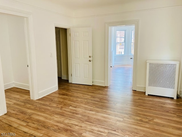 spare room featuring radiator and light hardwood / wood-style floors