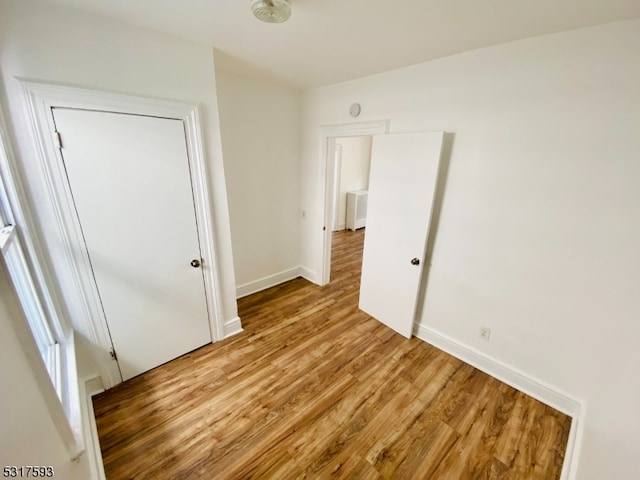 unfurnished bedroom with a closet, light hardwood / wood-style floors, and radiator