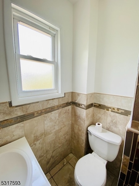 bathroom with tile walls and toilet