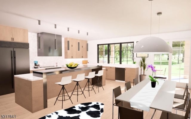 kitchen featuring pendant lighting, high end fridge, a kitchen island, a kitchen bar, and light brown cabinetry