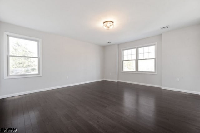 spare room featuring dark hardwood / wood-style floors and a healthy amount of sunlight