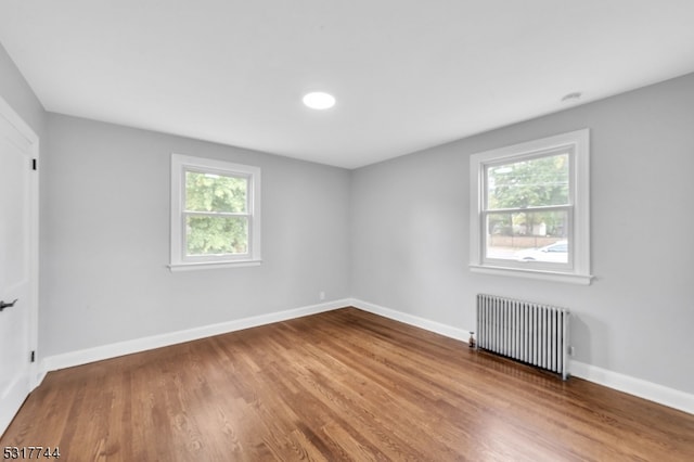 spare room featuring hardwood / wood-style flooring, plenty of natural light, and radiator heating unit