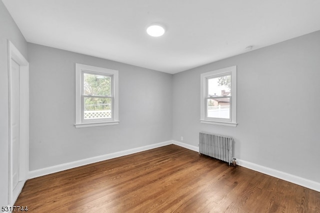 empty room with hardwood / wood-style flooring and radiator