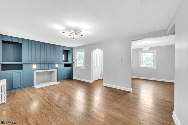 unfurnished living room featuring a notable chandelier, a healthy amount of sunlight, and hardwood / wood-style floors