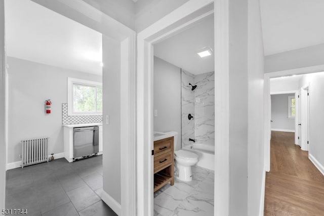 full bathroom featuring radiator, vanity, tiled shower / bath, toilet, and hardwood / wood-style floors