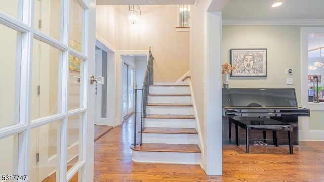 stairway with ornamental molding and wood-type flooring