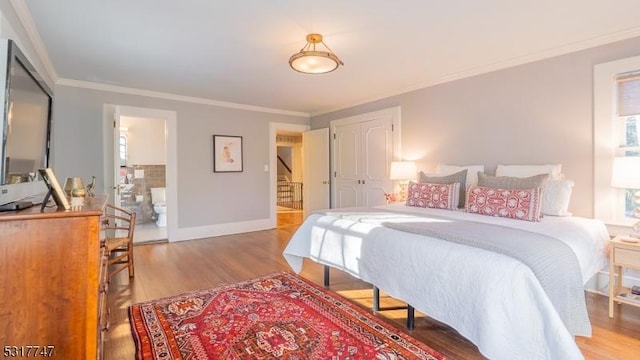 bedroom with hardwood / wood-style flooring, crown molding, and a closet