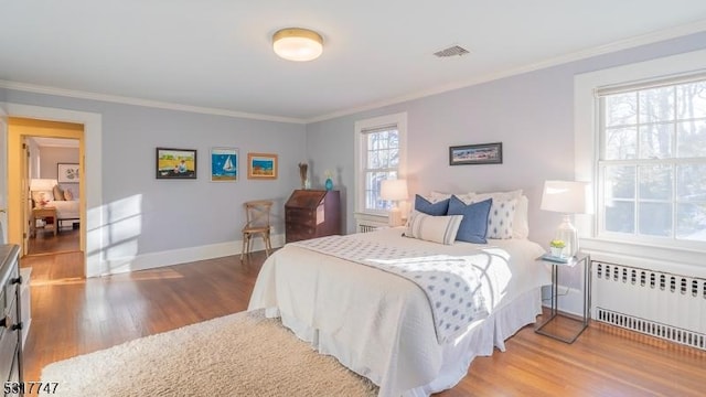 bedroom with ornamental molding, radiator, and hardwood / wood-style floors